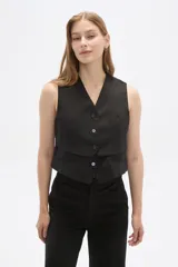 Chaleco negro sin mangas con escote en V y cierre frontal con botones. Diseño corto con solapas simuladas a la altura de la cintura.