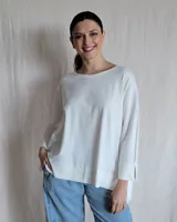 Remerón blanco de corte holgado, con cuello redondo y mangas largas con abertura en los puños.