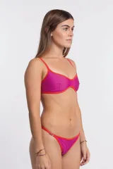 Bombacha de bikini colaless color fucsia con bordes y tiras laterales en color rojo. Los laterales son ajustables mediante hebillas metálicas.