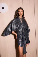 Vestido corto tipo kimono, color negro con brillo metálico (lurex), con mangas amplias y tiras ajustables en la cintura.