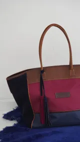 Bolso de fin de semana tipo tote bag, confeccionado en lona y gamuza, con detalles en cuero color marrón. Tiene un bolsillo interno con cierre.