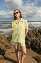 Camisa de lino a rayas verticales color naranja y blanco, de manga corta y corte oversize. Presenta bordados con motivos playeros en el frente y la espalda.