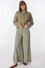 Cardigan color crudo de tejido de punto con diseño trenzado, cuello alto y cierre frontal con cremallera.