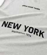 Musculosa negra de algodón con corte recto y hombros ligeramente ampliados (boxy fit). Presenta estampado frontal en blanco con el texto "URBAN SCENE TRENDS", "NEW YORK" y "Manhattan 1974".
