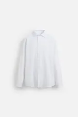 Camisa blanca de corte regular, cuello italiano, manga larga con puños abotonados y cierre frontal con botones.