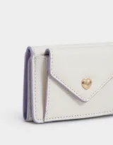 Billetera pequeña de cuerina color rosa claro con solapa en forma de sobre y broche de corazón dorado.