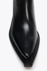 Bota de cuero negra de caña alta, con punta fina y tacón ancho.