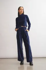 Pantalón de terciopelo azul marino, de corte sastrero amplio con pinzas, bolsillos laterales y largo al tobillo.