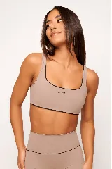 Top deportivo color beige con contorno negro, breteles anchos, corte slim y logo de la marca en el frente.