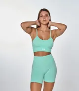 Conjunto deportivo color verde menta, compuesto por un top con breteles finos y logo 'bk.' estampado en el frente, y un short de ciclista de tiro alto.