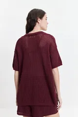 Camisa tejida color borgoña con textura calada, cuello clásico, botones y mangas cortas con elástico.