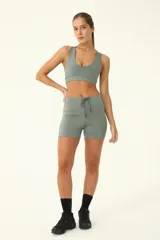 Top deportivo de compresión alta color verde, con escote pronunciado y espalda cruzada, diseñado para brindar soporte durante los entrenamientos.