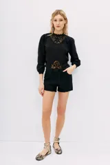 Short de jean negro con ruedo desflecado y tajo en los laterales.