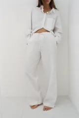 Pantalón largo de corte amplio, color blanco con finas rayas verticales negras, cintura elástica con cordón ajustable.