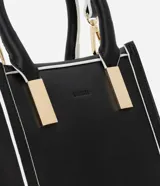 Bolso transversal pequeño tipo bandolera, color negro con detalles en blanco y herrajes dorados. Tiene correa de mano, asa larga desmontable y cierre superior.