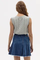 Chaleco tejido gris melange con diseño de ochos, cuello redondo y sisas amplias. Confeccionado en algodón y acrílico.