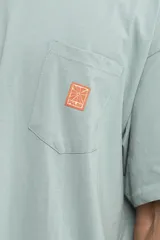 Remera color celeste con bolsillo en el pecho y logo estampado en color naranja.