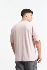 Remera color rosa claro de corte oversize y mangas cortas. Estampado frontal con la leyenda "Jungle Army", un tigre y otros símbolos.