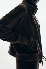 Campera corta de velour marrón oscuro, con cuello elevado, cierre frontal y bolsillos insertados al bies. Presenta elástico fruncido en puños y bajo.