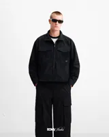 Campera bomber negra de gamuza sintética con cierre frontal, cuello alto, dos bolsillos superiores con solapa, puños y cintura ajustables.