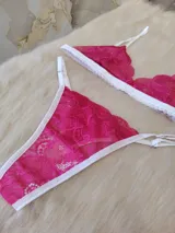 Conjunto de lencería fucsia de encaje floral, compuesto por un corpiño triangular sin aro y una tanga con tiras finas blancas.