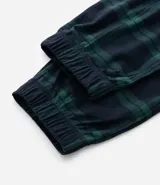 Pantalón de pijama de franela con estampa cuadrillé en tonos azul y verde. Tiene puños elásticos en los tobillos y cordón ajustable en la cintura.