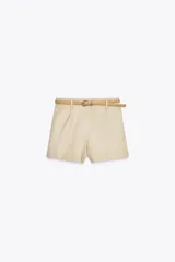 Bermuda color crema de tiro medio con pinzas delanteras y cinturón fino color beige. Tiene bolsillos frontales y falsos bolsillos de vivo en la espalda.