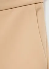 Pantalón de vestir color beige, de tiro medio y corte acampanado.