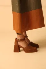 Sandalias negras de charol con plataforma, taco geométrico y pulsera al tobillo con hebilla metálica.