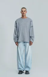 Sweater gris de manga larga con cuello redondo y costuras decorativas en los hombros y laterales.