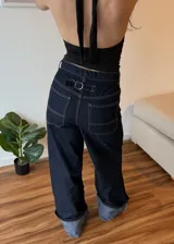 Pantalón de jean azul oscuro de corte ancho con dobladillo en color gris claro.