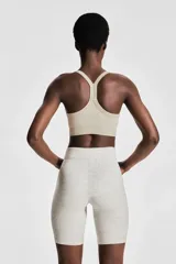Top deportivo color beige de tejido acanalado con tecnología DryMove™ que absorbe el sudor. Tiene breteles finos, espalda nadadora, copas forradas con relleno extraíble y bajo elástico acanalado.