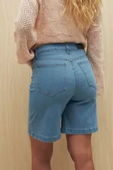 Bermuda de denim azul oscuro, de tiro alto y largo a la rodilla. Presenta bolsillos funcionales y costuras marcadas.
