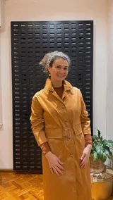 Gabardina color mostaza con cuello camisero, cierre frontal con botones y cinturón con hebilla.