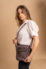 Morral bandolera color lila con correa ajustable, dos bolsillos frontales con cierre y dos bolsillos internos.