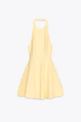 Vestido corto amarillo con cuello halter y espalda descubierta. Falda con vuelo y cierre trasero con cremallera oculta y botones ocultos en el cuello.