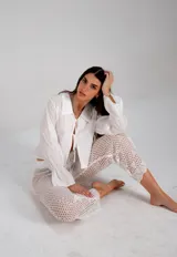 Pantalón largo de tejido calado en color blanco, con diseño de diversos puntos abiertos y corte recto levemente acampanado.