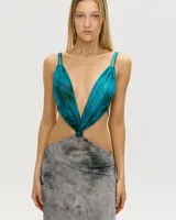 Vestido largo de corte irregular, con escote halter y espalda descubierta. La parte superior es de color turquesa y la falda es de color gris con estampado abstracto.