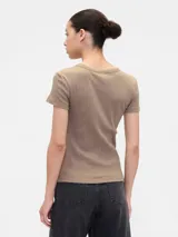 Remera color beige claro, de punto canalé con cuello redondo y mangas cortas. Corte ajustado al cuerpo.