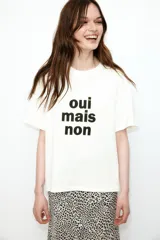 Remera blanca de corte amplio con estampado frontal de la frase "oui mais non" en color negro.