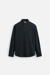 Camisa azul marino de algodón con textura jacquard, corte relaxed fit, cuello solapa, manga larga con puños abotonados y cierre frontal con botones.