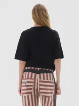 Remera de punto negra con cuello redondo y mangas cortas. Presenta un diseño de tejido con trenzas verticales.