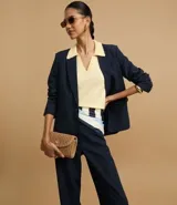 Pantalón de vestir azul marino, de corte recto, con bolsillos laterales y traseros. Se ajusta a la cintura con cinturón de cuero marrón.