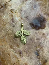 Dije de bronce con forma de rama con tres hojas.