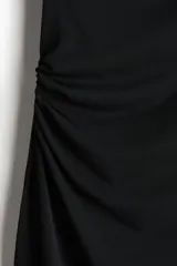 Vestido midi negro sin mangas en punto elástico con leve brillo. Modelo ajustado con frunces en escote, hombros y en un lateral de la cintura para crear un efecto drapeado.
