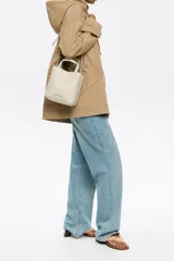 Bolso tote pequeño de piel reconstituida color gris claro, con estructura rígida, doble asa corta, correa extraíble, cierre con botón de presión, logo metálico BIMBA Y LOLA, acabados metálicos, bolsillo interior con cierre de cremallera e interior con logo grabado.