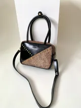 Cartera rígida color marrón con estampado animal print, detalles en charol negro y tachas doradas. Tiene doble asa corta, correa larga extraíble y cierre metálico plateado. El interior está forrado y tiene un bolsillo con cierre y un bolsillo plaqué.