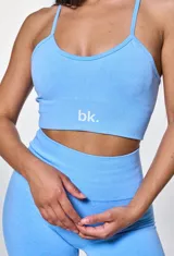 Conjunto deportivo celeste compuesto por un top con breteles finos y logo 'bk.' estampado en blanco, y un short de calce ajustado.