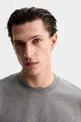 Camiseta gris de algodón, corte recto, cuello redondo y manga corta.