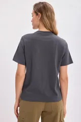 Remera gris con cuello redondo y manga corta. Estampado frontal con dos serpientes entrelazadas y texto en blanco que dice 'Not everything is what it seems'.